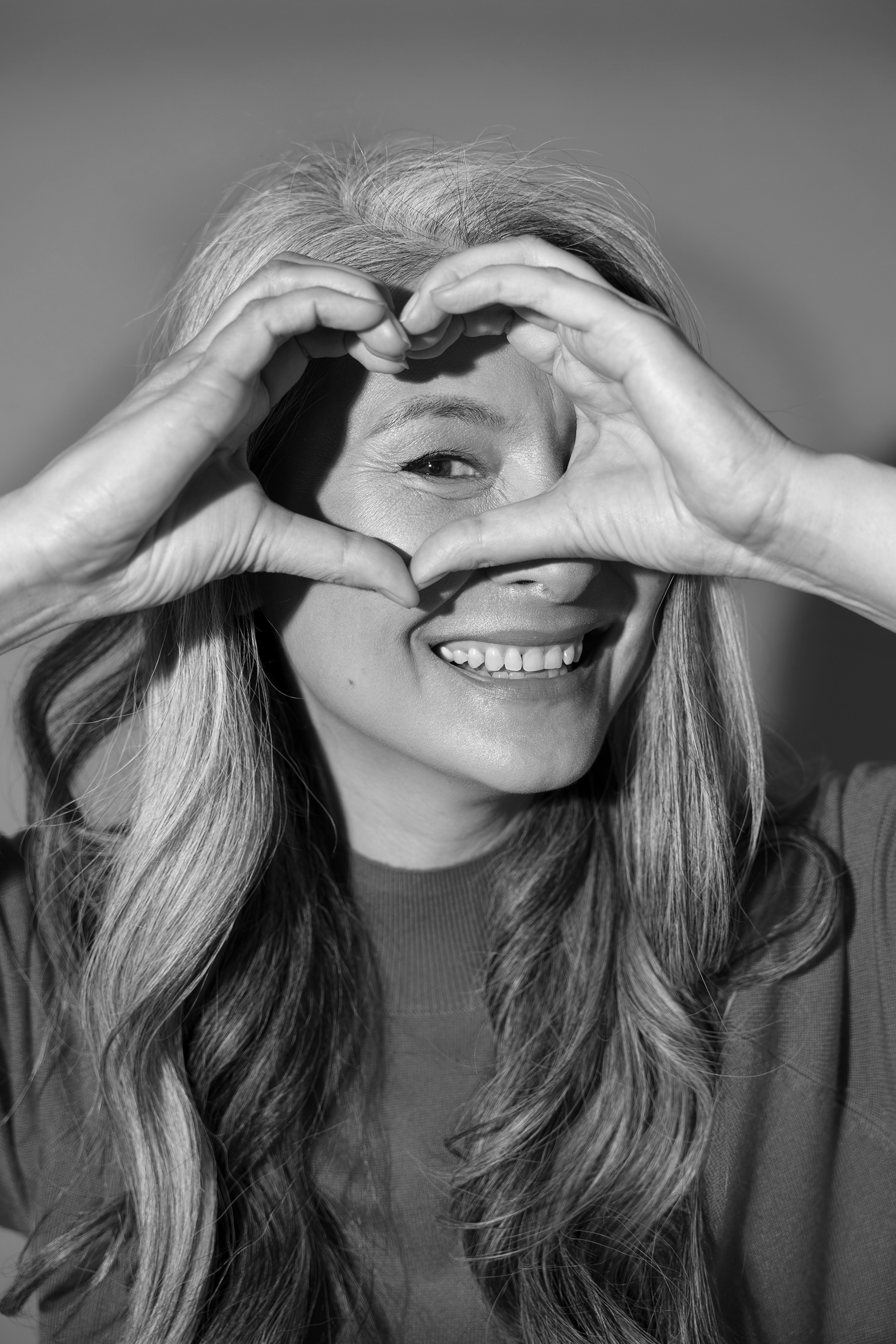 Paciente sonriendo y formando un corazón con las manos.
